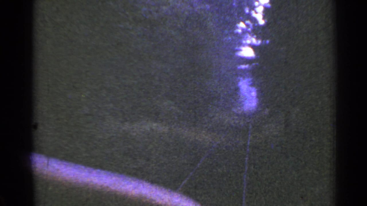 1953 Connecticut 8mm frame looking forward from a train along wooded railroad tracks, with bright overexposure near the horizon.