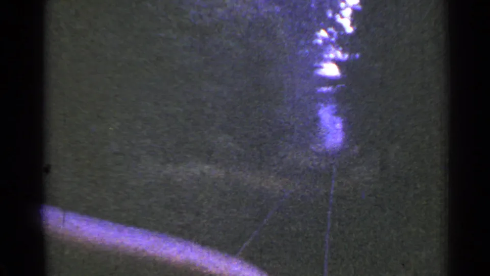 1953 Connecticut 8mm frame looking forward from a train along wooded railroad tracks, with bright overexposure near the horizon.