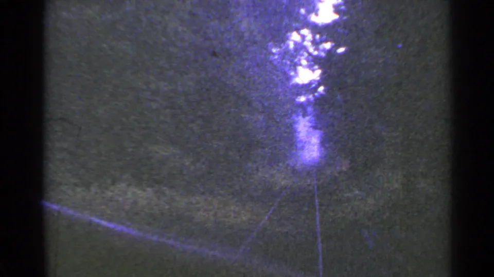 Forward-looking 8mm view from a train in Connecticut, with rails curving through trees toward a blown-out bright area.