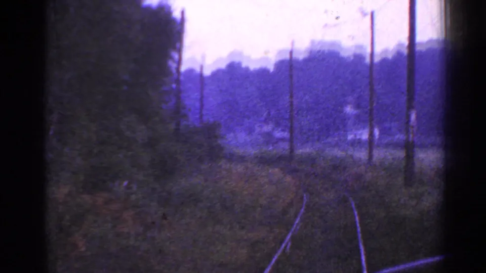 1953 Connecticut countryside rail view with tracks bending past utility poles, brush, trees, and hazy hills in the distance.