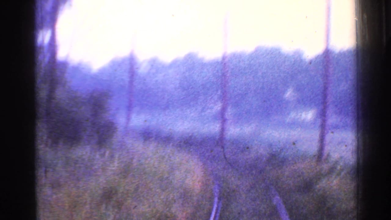 1953 Connecticut 8mm view from a moving train with rails, telephone poles, grassy banks, and distant trees.