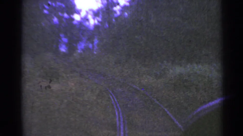 The rail line curves through a wooded rural Connecticut landscape, rendered with purple-blue color shift and heavy 8mm grain.