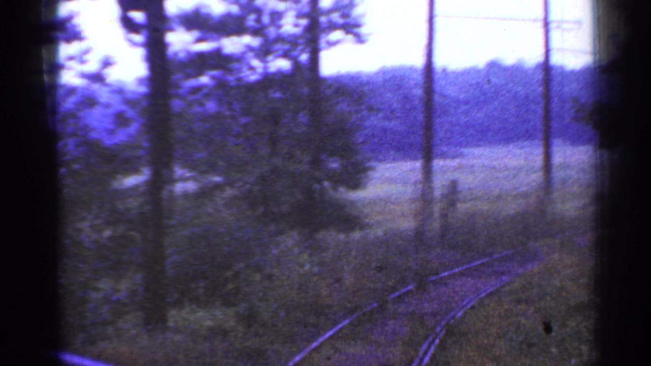 1953 Connecticut train-window view of curving rural tracks, telephone poles, fields, and distant wooded hills.