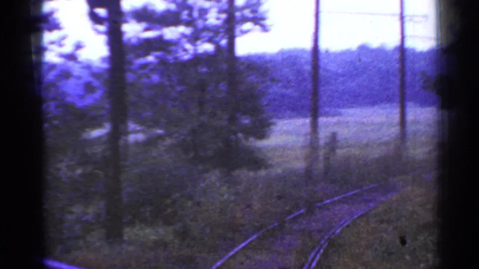 1953 Connecticut train-window view of curving rural tracks, telephone poles, fields, and distant wooded hills.