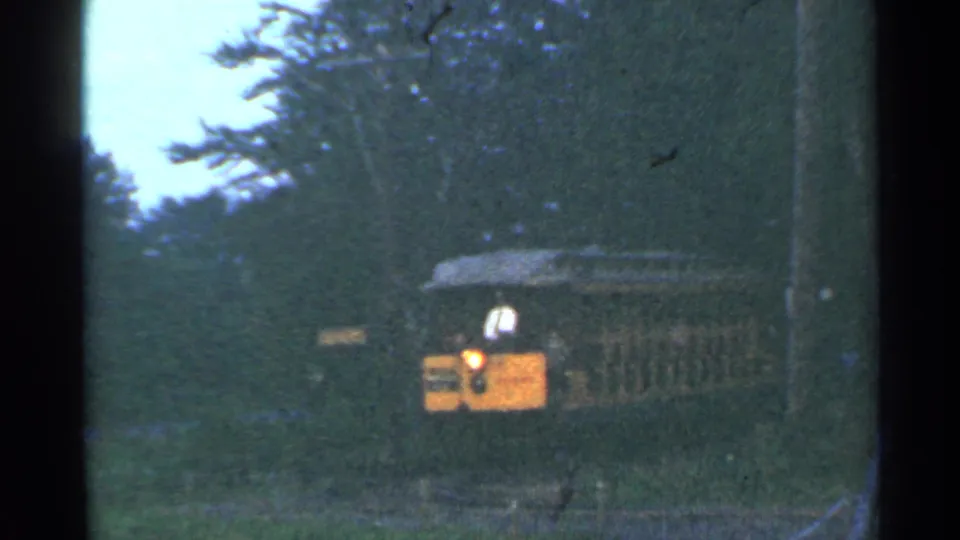 The 1953 Connecticut sightseeing train continues through the wooded area, with its open car and headlight visible on grainy 8mm film.