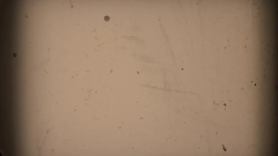 Mostly blank beige 8mm frame showing dust, scratches, uneven exposure, and a dark frame edge at left.