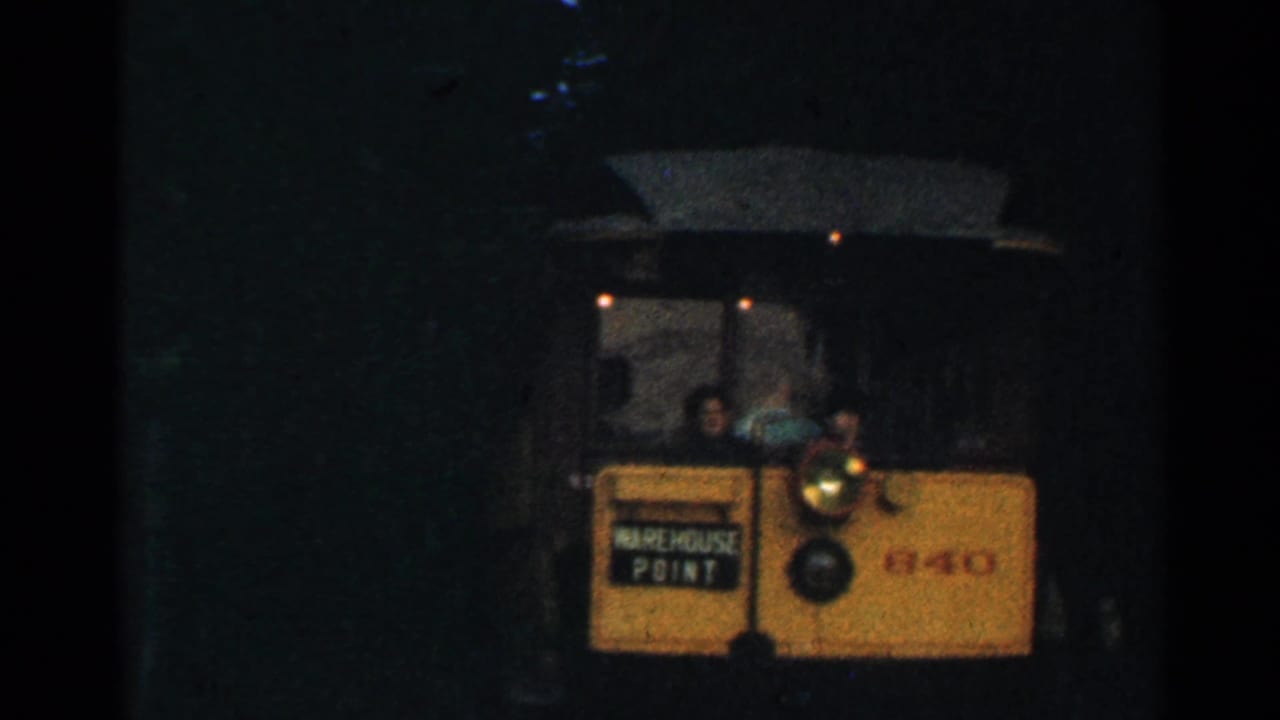 1953 Connecticut 8mm frame showing a yellow trolley at a dark tunnel entrance with its WAREHOUSE POINT sign and headlamp visible.
