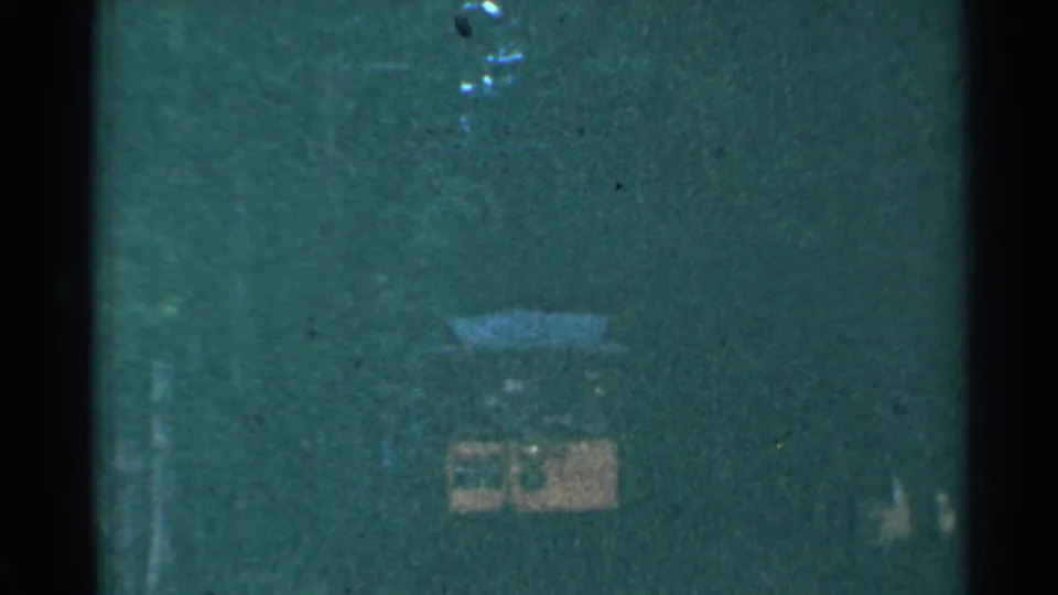 The trolley is barely visible in the dark tunnel, with only its yellow front and sign area catching the remaining light.