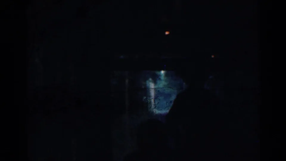 Dark final frame from the 1953 Connecticut trolley clip, with small highlights and a blue-green illuminated patch amid deep shadow.