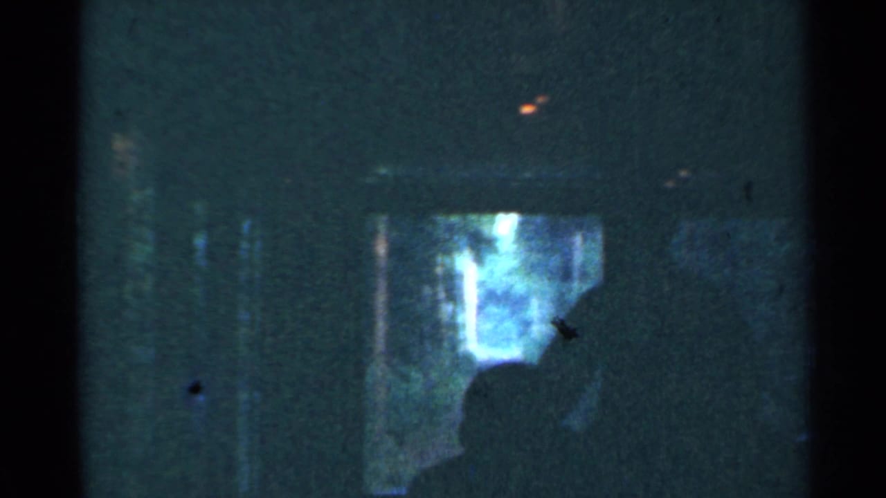 1953 Connecticut 8mm frame showing a dim train interior, a passenger silhouette, and blurred trees beyond the window.