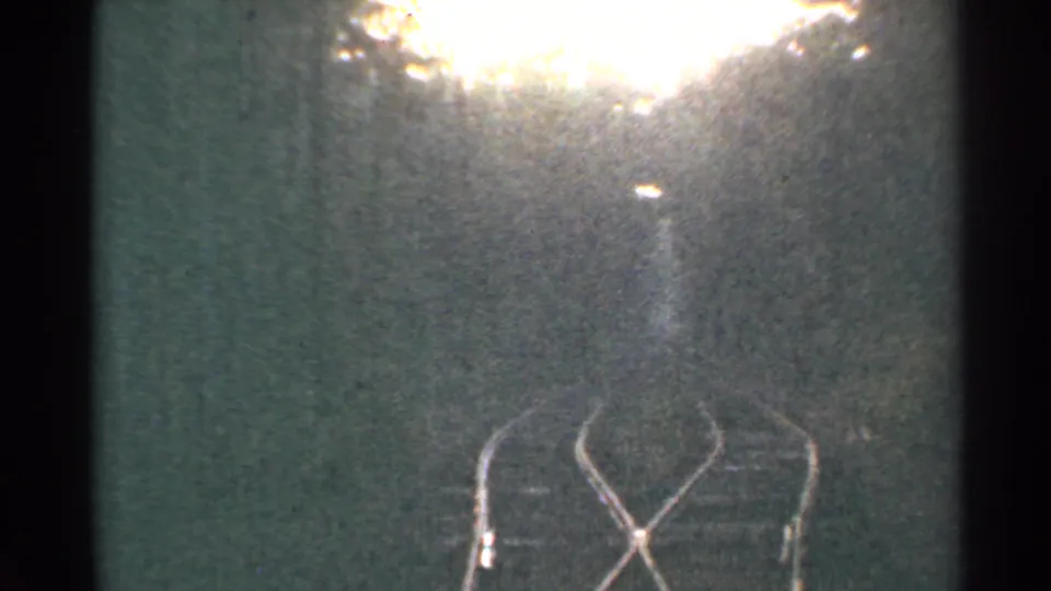 1953 Connecticut 8mm frame of rails and track bed, partly obscured by bright exposure bloom and home-movie grain.