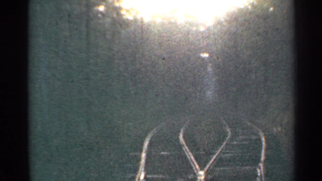 1953 Connecticut 8mm frame showing a passenger-view look ahead at rails and trees with bright flare near the top edge.