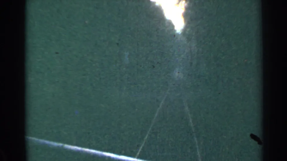 1953 Connecticut 8mm frame with a large white flare over a green surface, plus scratches, grain, and visible film gate borders.