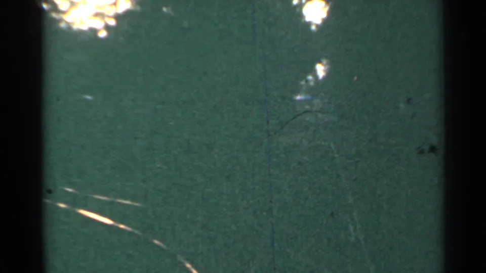 1953 Connecticut 8mm frame with green tint, black vertical frame edge, grain, scratches, and a bright streak low in the scene.