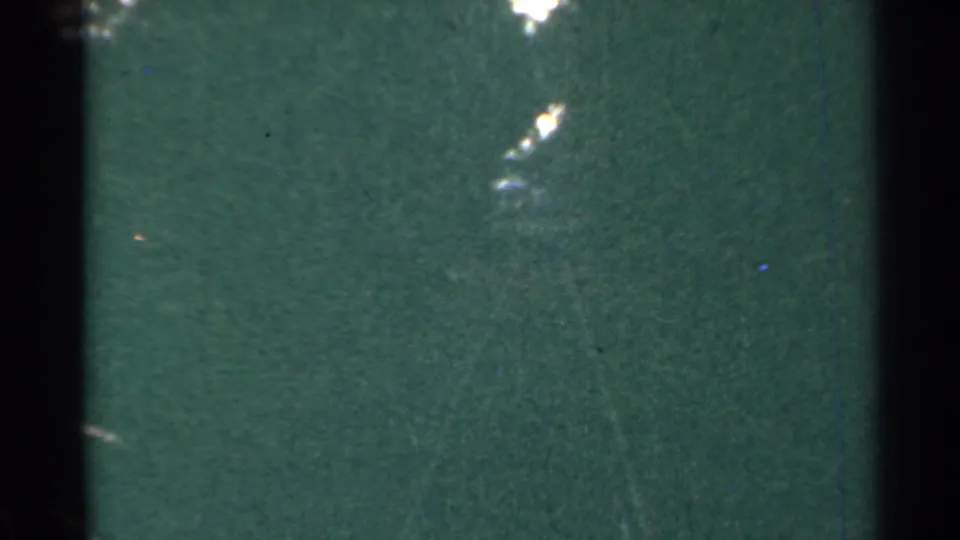 1953 Connecticut 8mm frame with a dark green surface, soft tree-filtered highlights, grain, and black film-edge shading.
