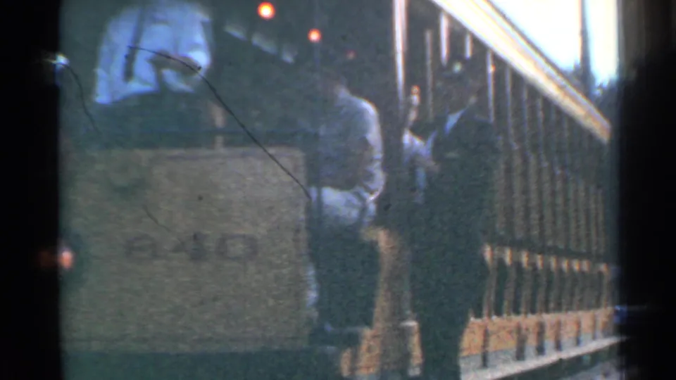 A closer 1953 Connecticut trolley view shows the front corner, seated passenger, side railings, warm interior lights, and soft film grain.