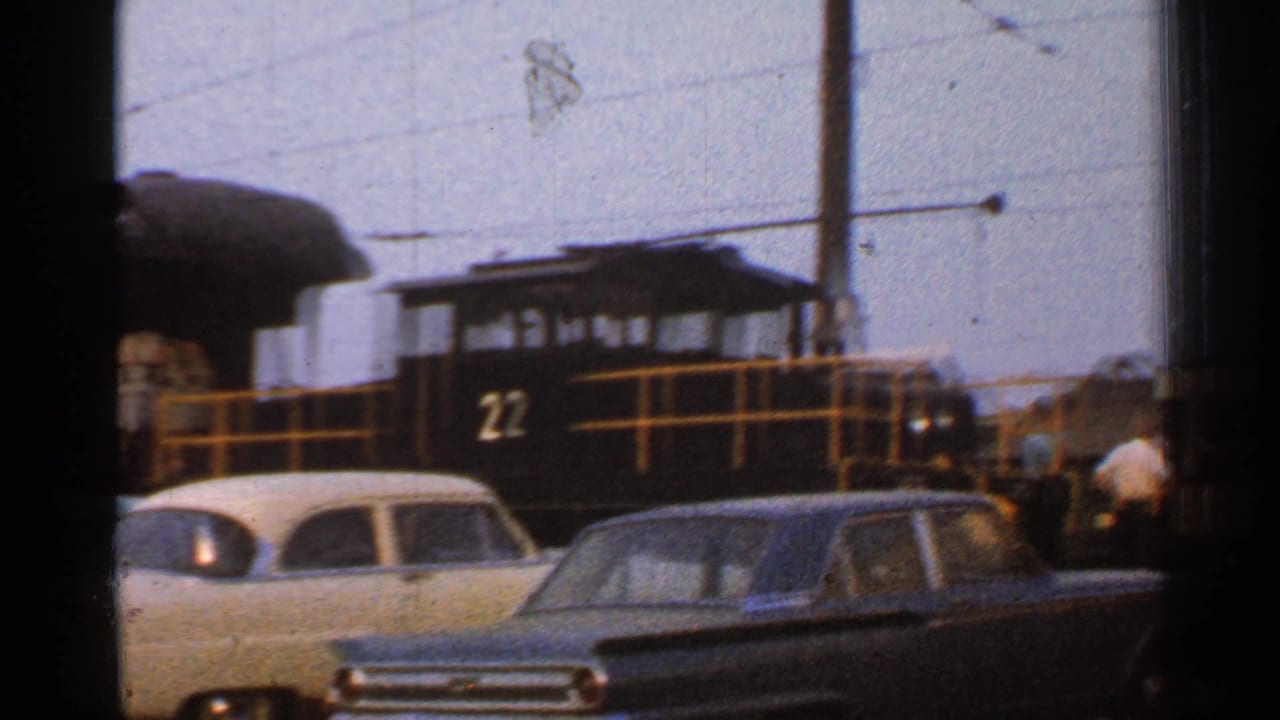 1953 Connecticut train-yard view with a black locomotive numbered 22, yellow railings, and parked mid-century cars.