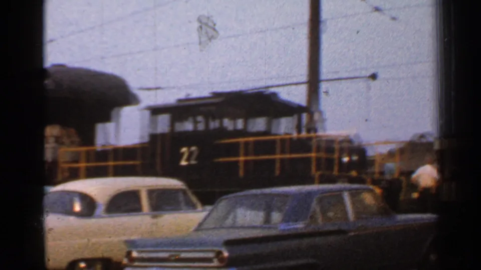1953 Connecticut train-yard view with a black locomotive numbered 22, yellow railings, and parked mid-century cars.