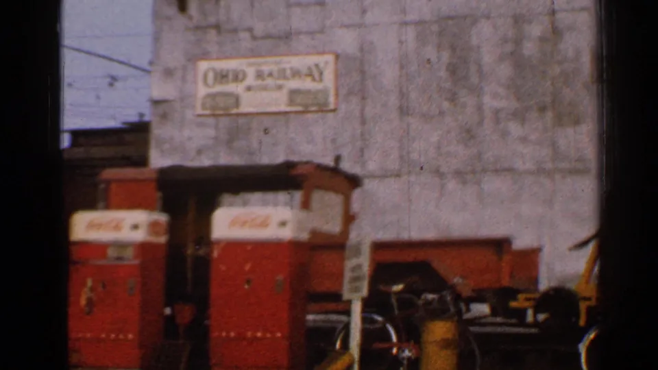 1953 Connecticut 8mm frame showing red Coca-Cola vending machines, a bicycle, and an Ohio Railway sign on a weathered industrial wall.