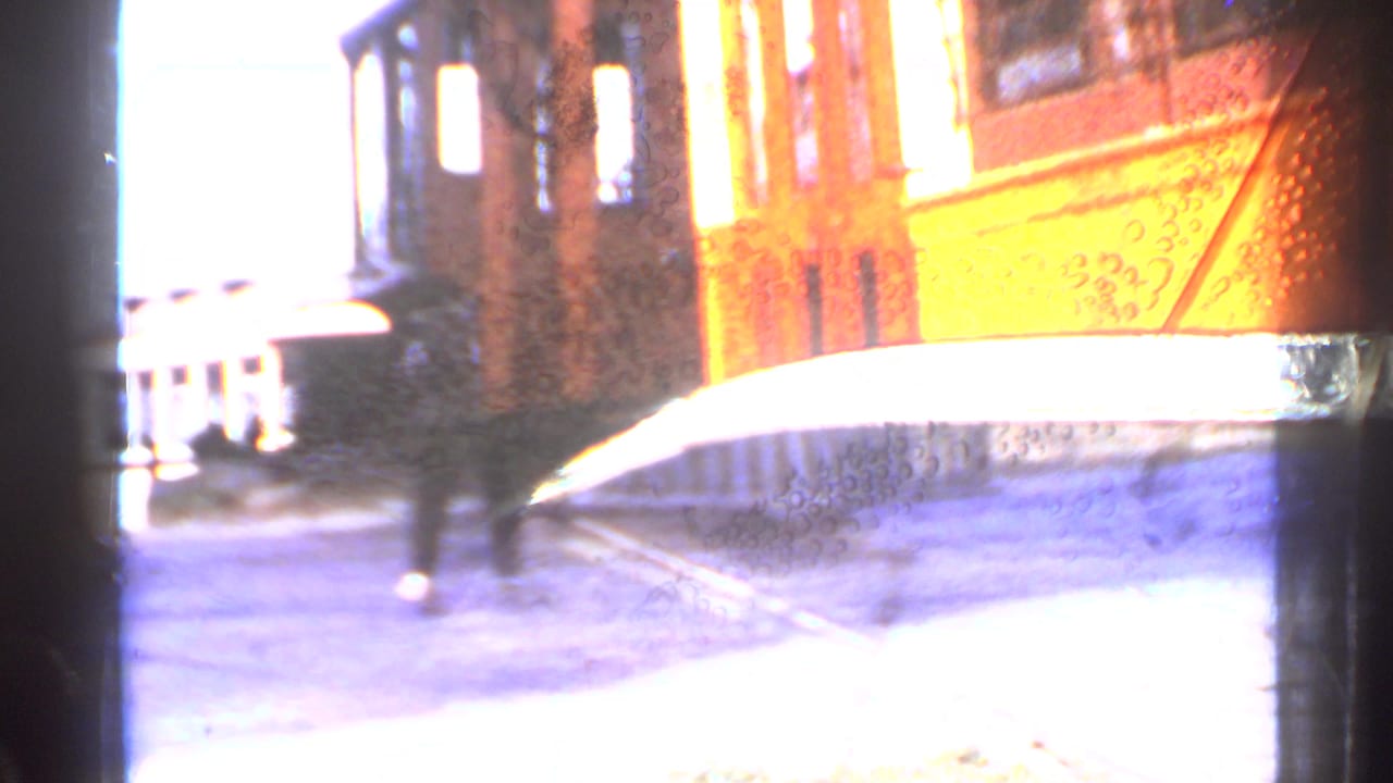 1953 Connecticut 8mm frame showing a close, blurred view of an orange trolley moving beside tracks.