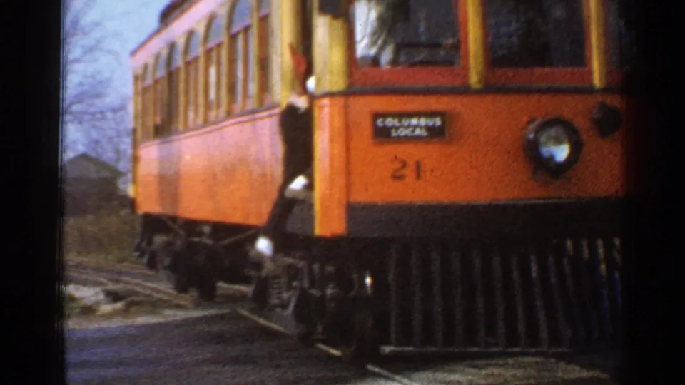 Close view of the orange Columbus Local trolley number 21 moving along rail tracks in 1953 Connecticut footage.