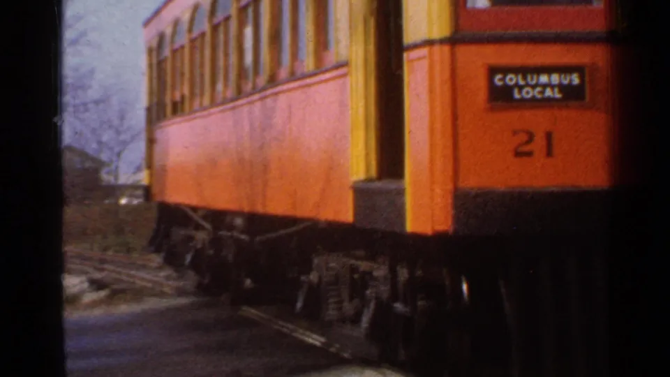The orange trolley marked Columbus Local and 21 continues past the camera on tracks in Connecticut.