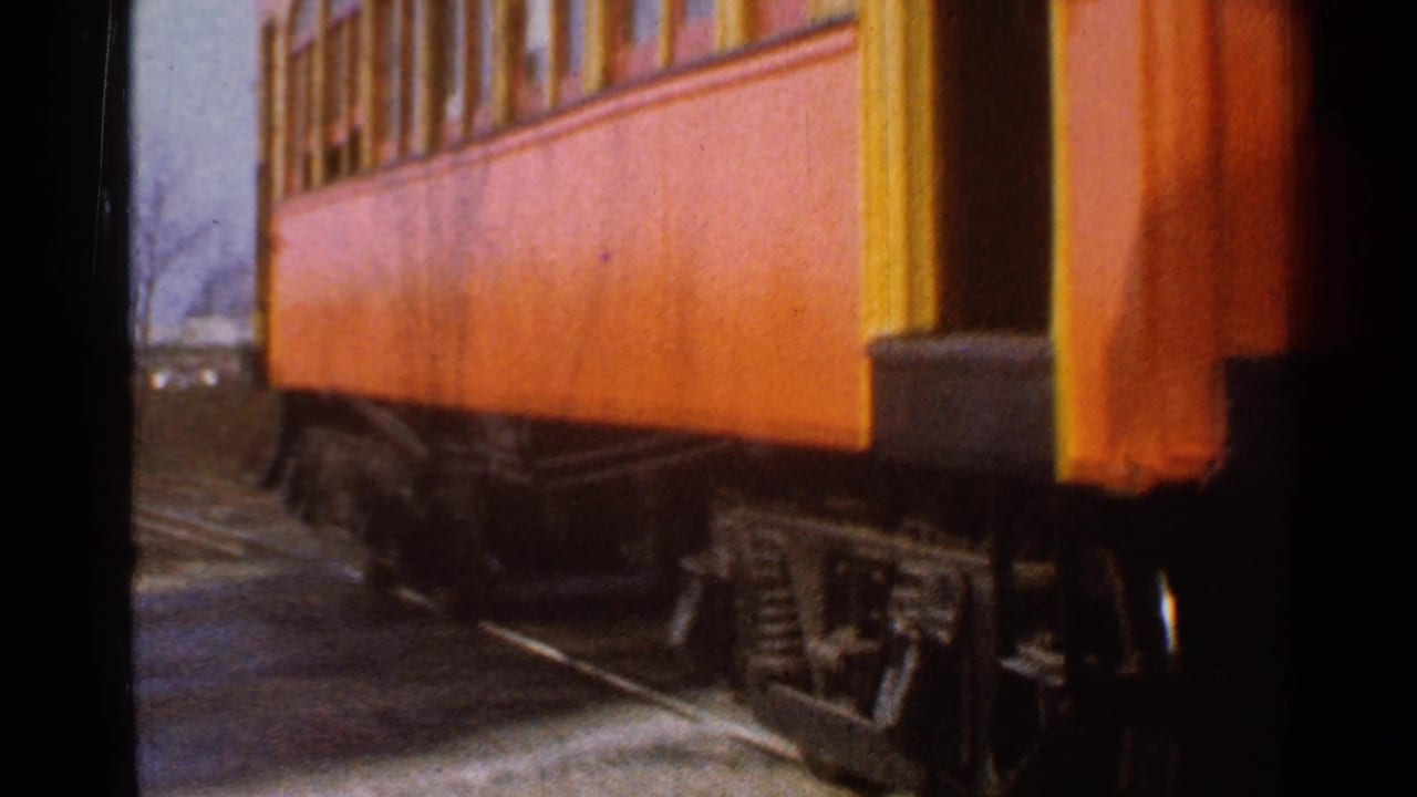 1953 Connecticut 8mm frame showing an orange and yellow rail car moving past the camera with wheels and track visible below.