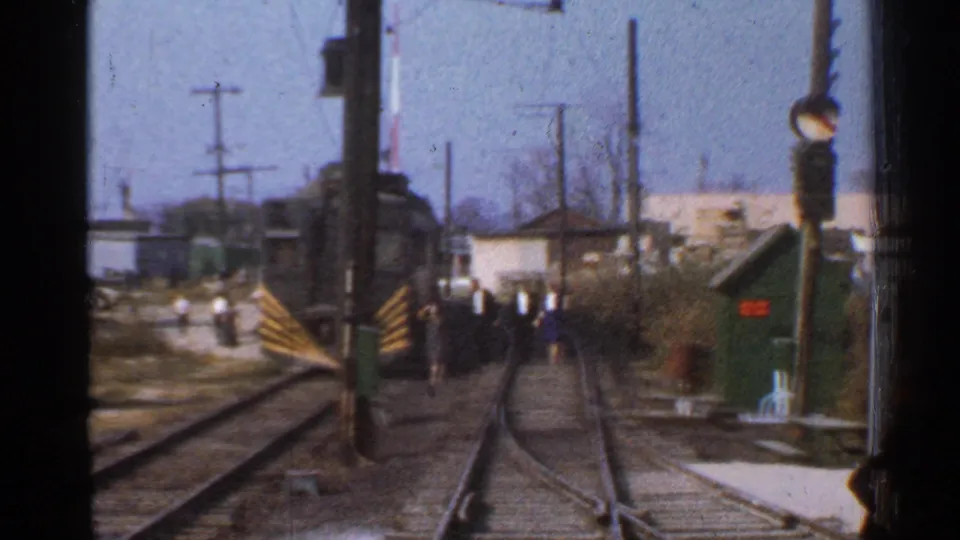 1953 Connecticut rail-yard frame with multiple tracks, utility poles, distant buildings, and small visible people near the right side.