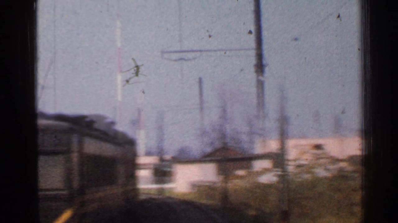 1953 Connecticut passenger-window view showing a nearby rail car, curving tracks, utility poles, low buildings, and winter-bare trees.