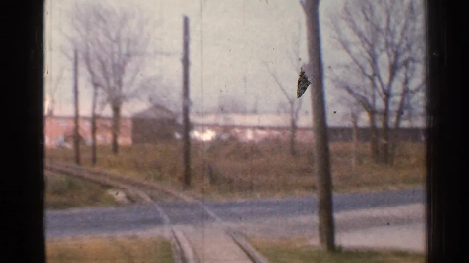 Connecticut train POV from 1953 with rails leading toward a road crossing, utility poles, open trackside ground, and bare trees.