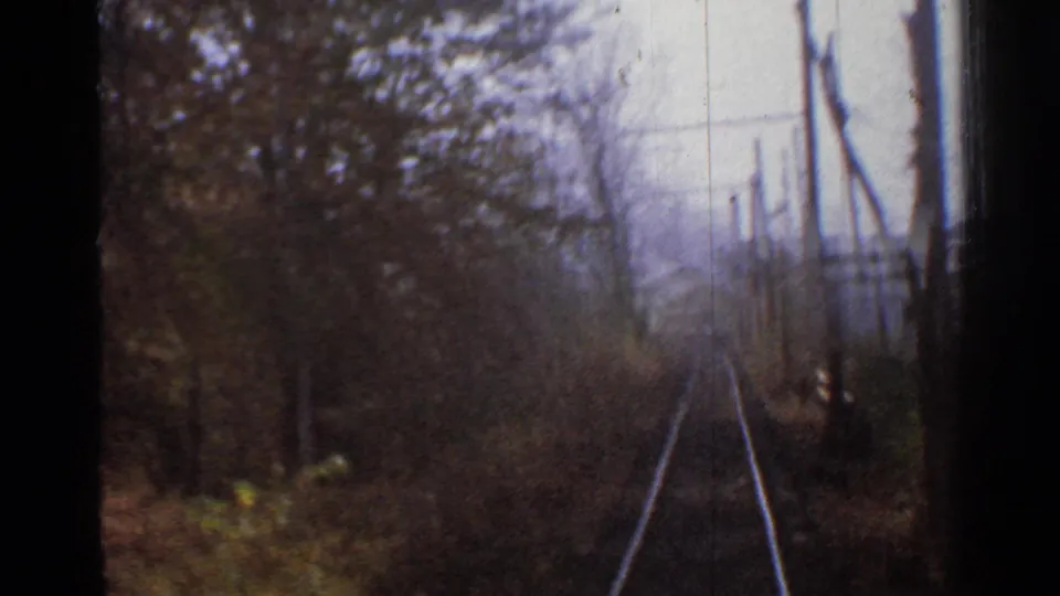 1953 Connecticut 8mm frame looking ahead along railway tracks through a wooded corridor with utility poles at the right.