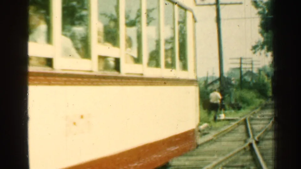 Home-movie view of the trolley side continuing past trackside rails, trees, poles, and a small distant figure in Connecticut.