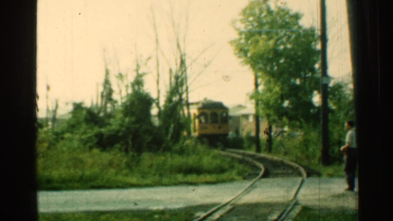 1953 Connecticut trolley car approaches around a curve while an adult man stands near the roadside track area.