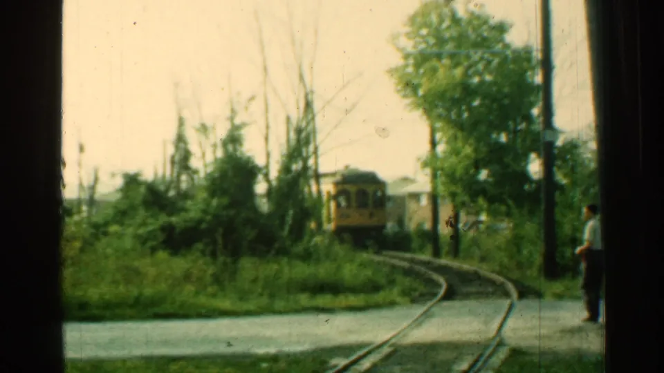 1953 Connecticut trolley car approaches around a curve while an adult man stands near the roadside track area.