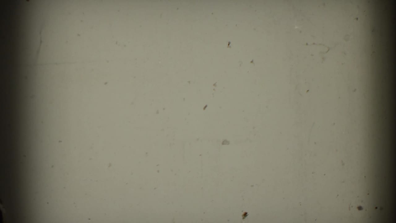 A mostly blank 8mm frame from the supplied 1953 clip, showing film grain, dust, scratches, vignetting, and a dark vertical gate edge.