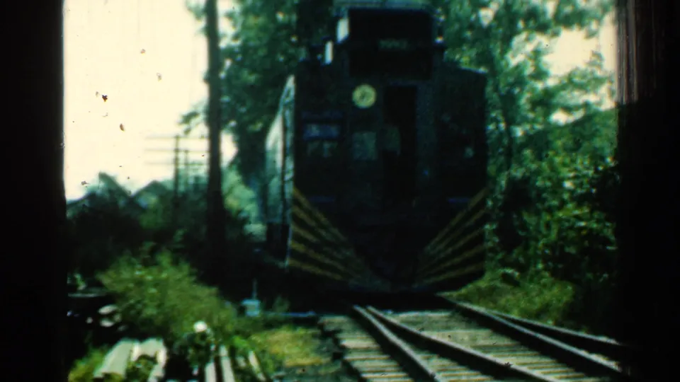 1953 Connecticut 8mm frame showing the dark front of a train with a circular headlight approaching on rails.