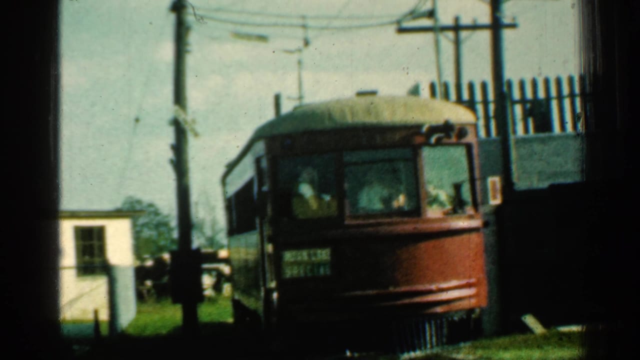 Front of a red trolley marked SPECIAL passing near a small white building and utility poles.