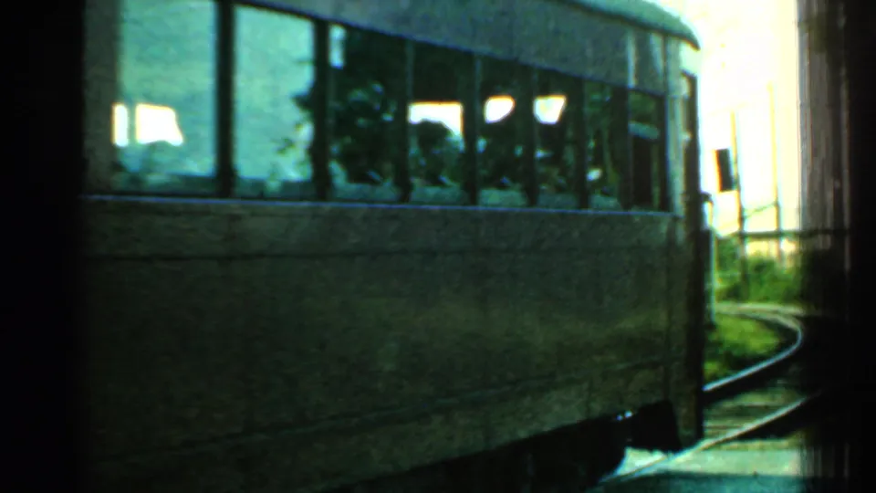 Close view of the trolley side and windows in 1953 Connecticut footage, with indistinct passenger silhouettes and a curve of track beside it.