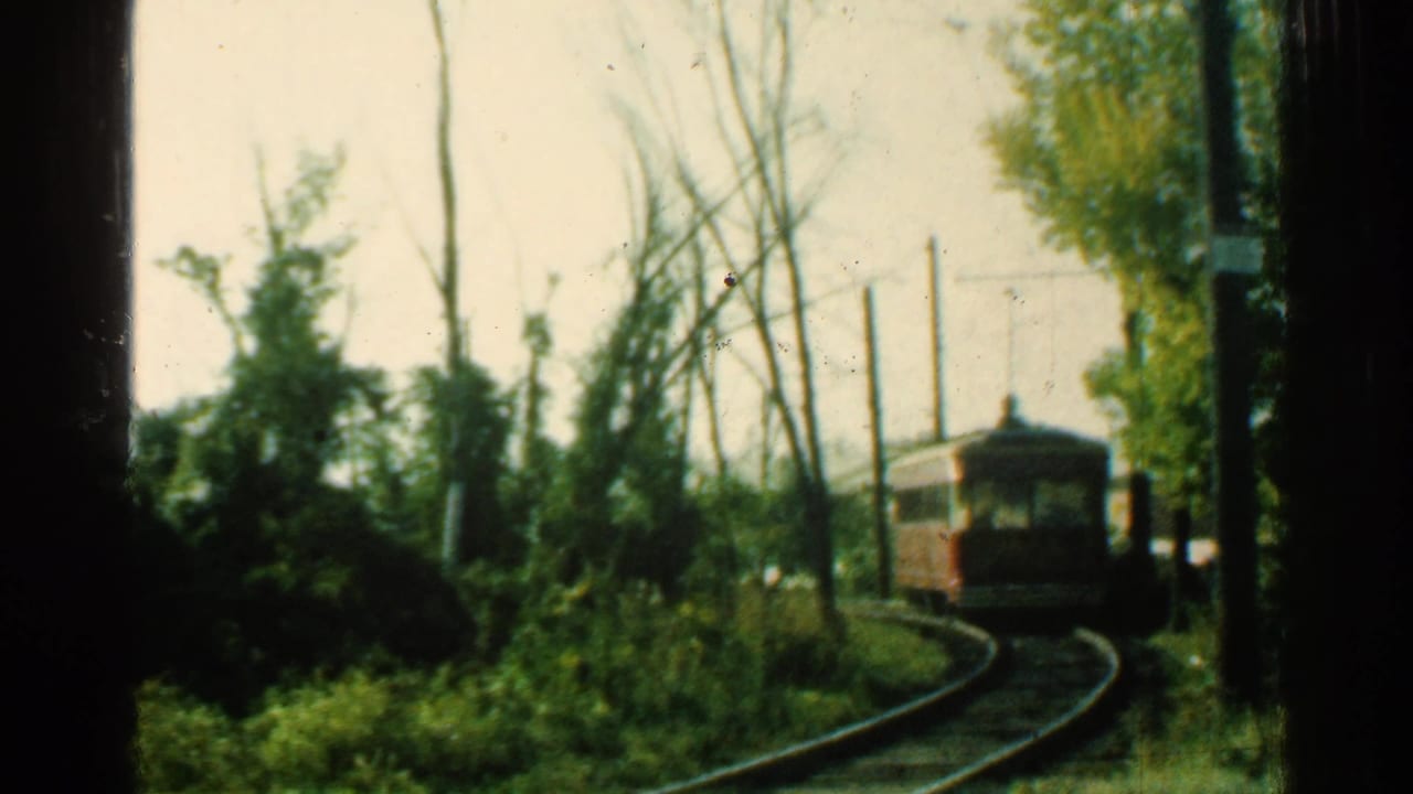 1953 Connecticut 8mm frame showing a red trolley car moving along curved rails through green foliage and utility poles.