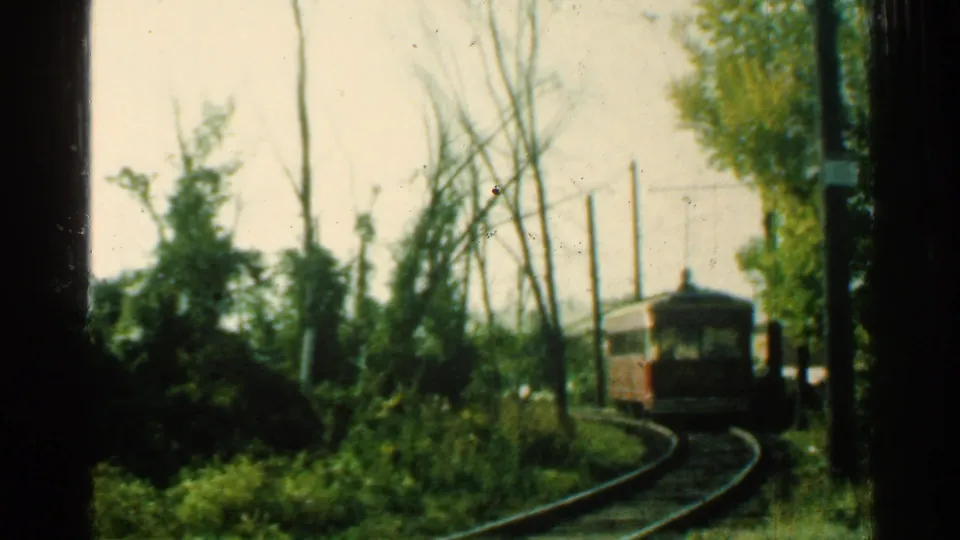 1953 Connecticut 8mm frame showing a red trolley car moving along curved rails through green foliage and utility poles.