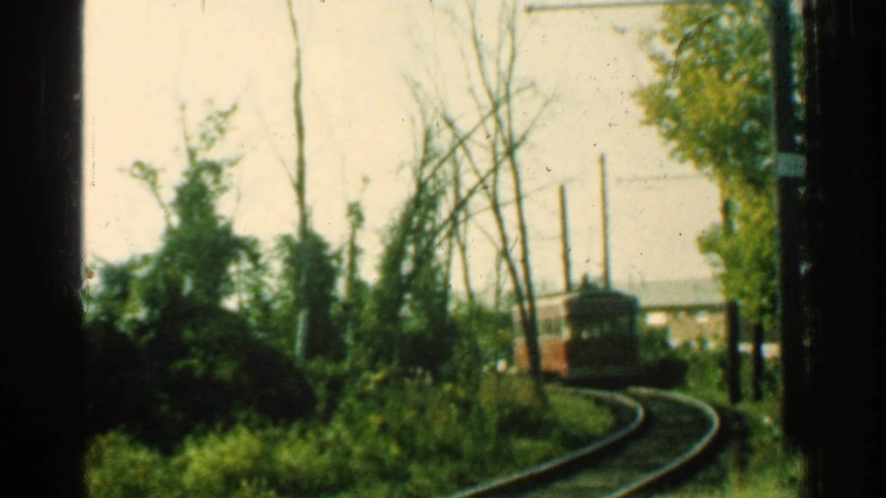 1953 Connecticut frame of a red trolley on curved track beside trees, poles, and overhead wire infrastructure.