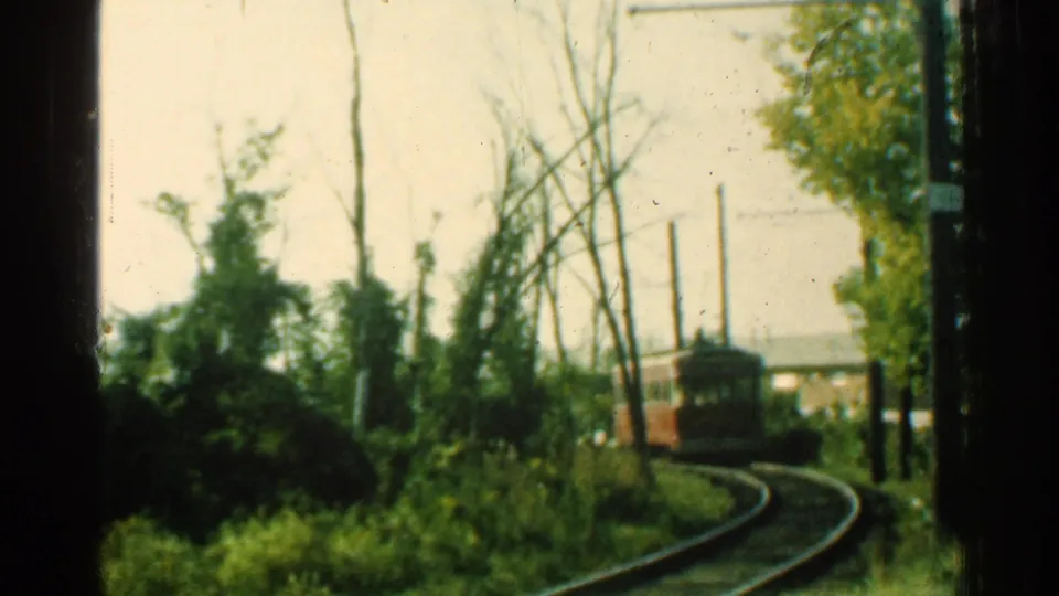 1953 Connecticut frame of a red trolley on curved track beside trees, poles, and overhead wire infrastructure.
