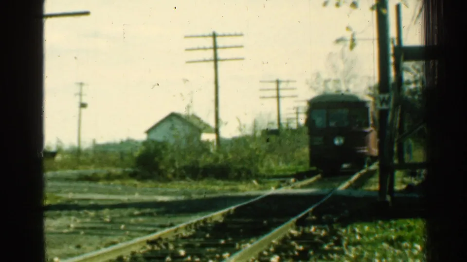 1953 Connecticut 8mm frame with the red trolley advancing toward the camera along rural rails near a small house and utility poles.