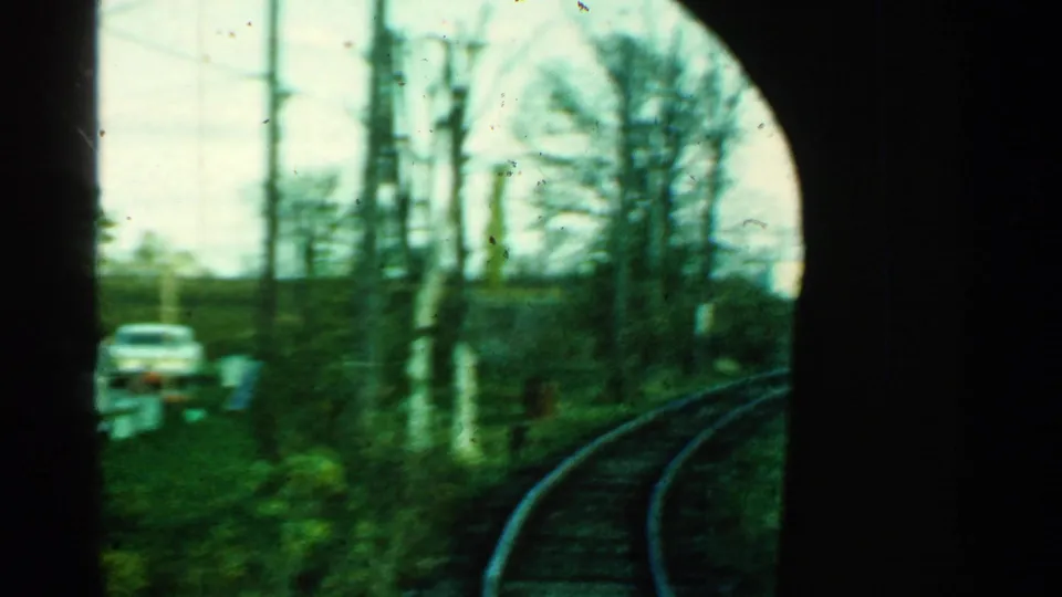 Connecticut countryside rail view from 1953 with a car near the trackside, utility poles, bare trees, and a curved rail line.
