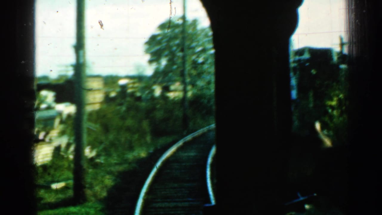 Passenger-window view in Connecticut, 1953, showing the train following a sharp rail curve past poles and rural greenery.