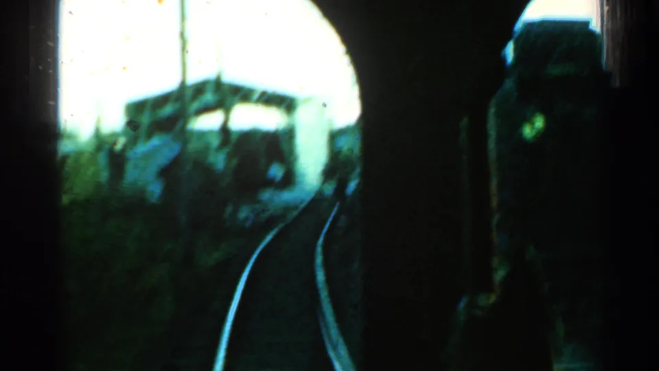 1953 Connecticut 8mm train-window view with rails curving past a concrete bridge or overpass and surrounding greenery.