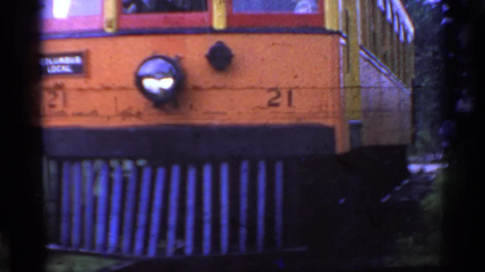 Grainy 1953 Connecticut frame of trolley number 21 passing close, with the front corner, windows, and side railing visible.