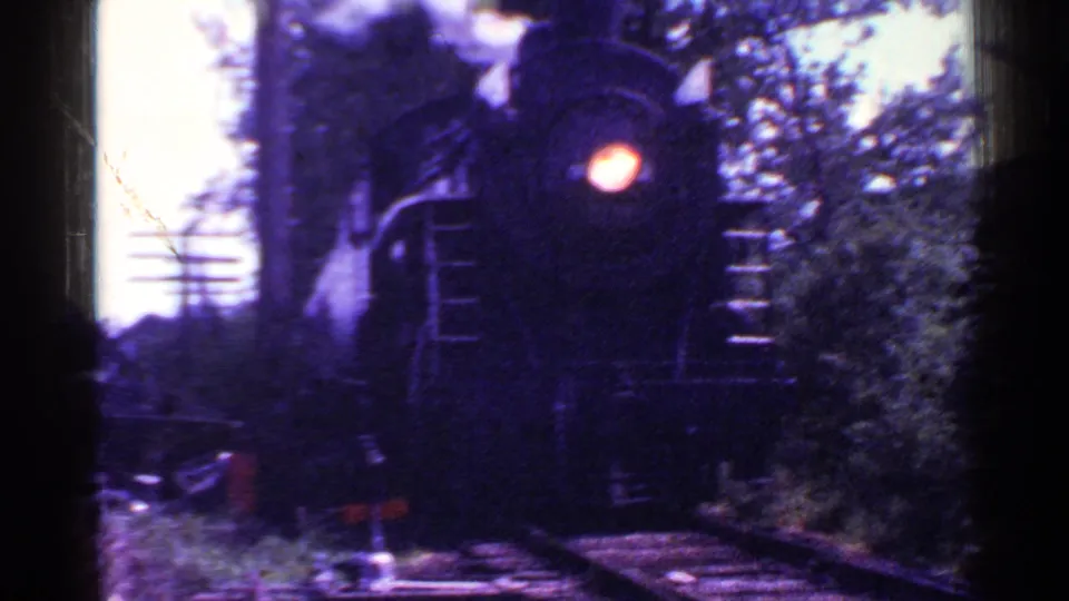 The steam locomotive fills much of the frame, its headlight prominent as it passes along the wooded Connecticut track.