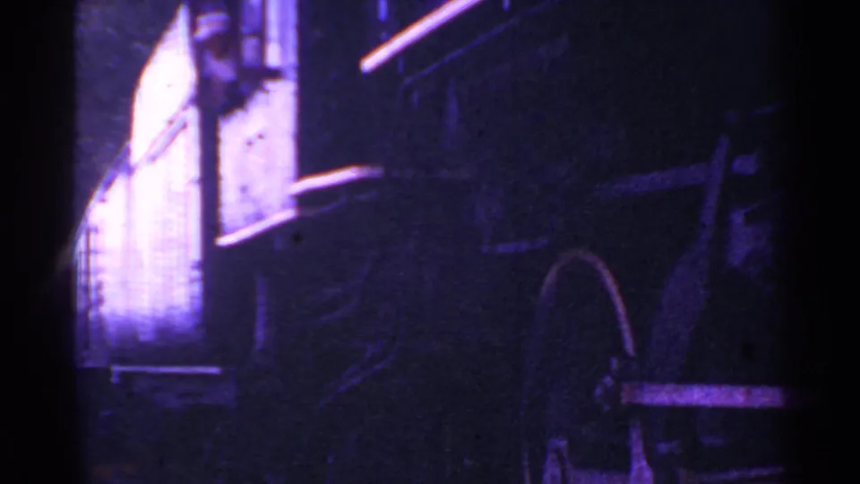 1953 Connecticut 8mm frame with the side of a railcar, a wheel-like form, and strong shadow in purple-blue low light.