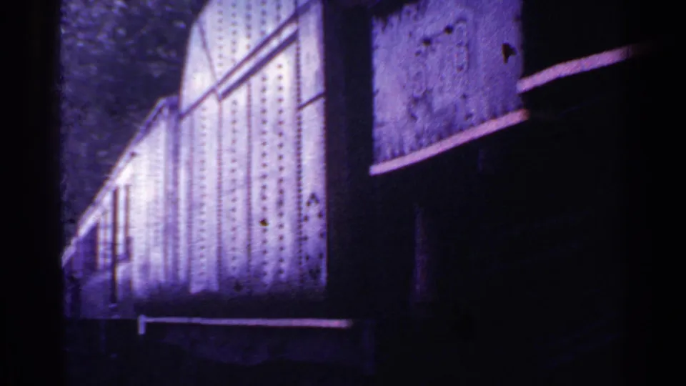 1953 Connecticut 8mm frame of a close railcar side, with a bright paneled area, diagonal metal line, and deep shadow.